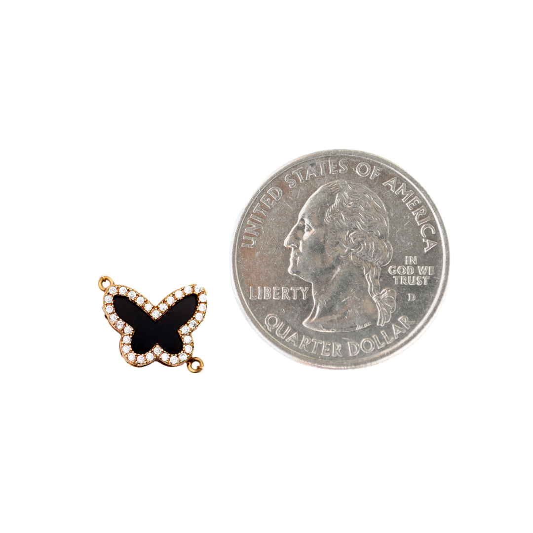 The butterfly charm displayed alongside a quarter to offer perspective on its actual size