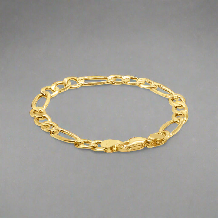 A gold Figaro chain bracelet with a classic and elegant design. The bracelet features a distinctive pattern of interlocking links, alternating between one elongated oval link and three smaller round links, characteristic of the Figaro style. Each link is polished to a high shine, enhancing the bracelet's luxurious appearance. The bracelet is secured with a sturdy lobster clasp, ensuring durability and ease of use. Its smooth surface and intricate link pattern reflect exceptional craftsmanship. 